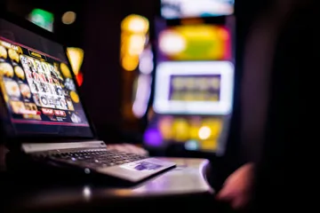 A woman smiling by bright slot machines showing lucky symbols, showcasing the exciting slot offerings at PARIPULSE.